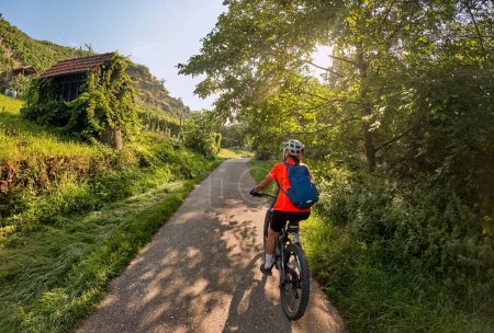 Foto de Agradable mujer con bicicleta de montaña eléctrica, ciclismo en la luz de la mañana en el valle del Neckar carril bici cerca de Ludwigsburg, Baden Wrttemberg, Alemania - Imagen libre de derechos