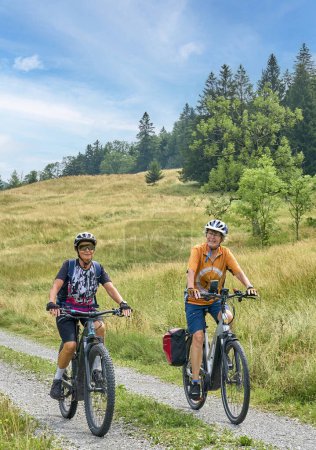 Foto de Dos amigas mayores divirtiéndose durante un recorrido en bicicleta por el bosque de Bregenz cerca de Sibratsgfll, Vorarlberg, Austria - Imagen libre de derechos
