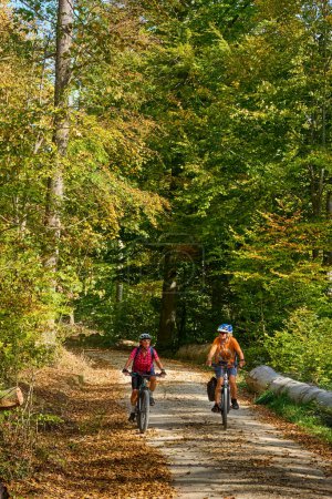 Téléchargez les photos : Belles copines âgées faisant du vélo avec leurs vélos électriques dans la forêt automnale de la Schwaebische Alb à Baden-Wuerttemberg, Allemagne - en image libre de droit