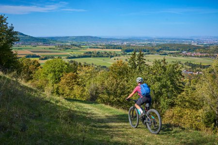 nice  active senior woman, riding her electric mountainbike in the gold colored autumn forests of the Swabian Alb
