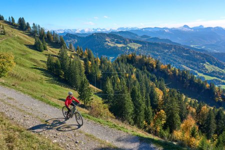 mujer activa montando su bicicleta de montaña eléctrica en las montañas del bosque de Brengenz cerca de Hittisau, Vorarlberg, Austria