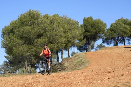 Nette, aktive Seniorin mit ihrem Elektro-Mountainbike in den Kiefernwäldern in der Nähe von Granada, Andalusien, Spanien