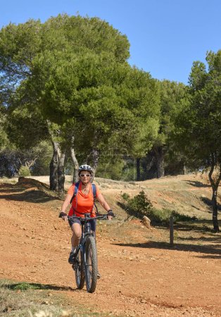 Nette, aktive Seniorin mit ihrem Elektro-Mountainbike in den Kiefernwäldern in der Nähe von Granada, Andalusien, Spanien
