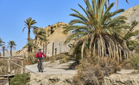 Téléchargez les photos : Belle femme âgée active avec son vélo de montagne électrique lors d'un tour de piste dans le désert de Tabernas près d'Almeria, Andlusia, Espagne - en image libre de droit