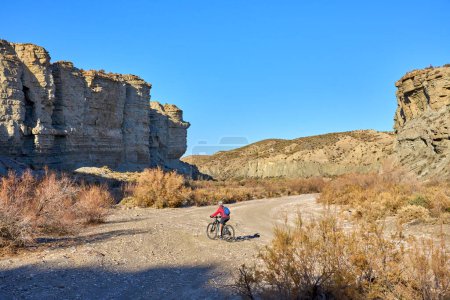 Foto de Mujer mayor agradable y activa con su bicicleta de montaña eléctrica en un recorrido por el desierto de Tabernas cerca de Almería, Andlusia, España - Imagen libre de derechos