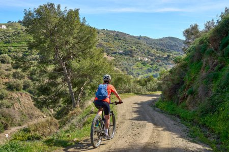 Schöne Frau radelt mit ihrem Elektro-Mountainbike in der Sierra de Tejada bei Nerja, Andalusien, Spanien