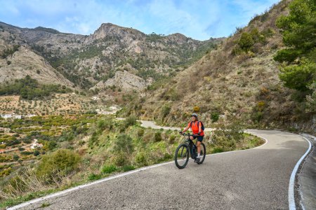 Foto de Bonita mujer en bicicleta con su bicicleta de montaña eléctrica en la Sierra de Tejada cerca de Nerja, Andalucía, España - Imagen libre de derechos