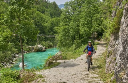 Photo for Nice senior woman on a bike tour along  River Soca with her electric mountain bike  in the Triglav National Park in Slovenia - Royalty Free Image