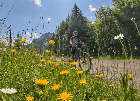 Photo for Cheerful active senior woman on a E mountain bike tour at Vri Pass in the Triglav National Park, Julian Alps above Kranska Gora in Slovenia - Royalty Free Image