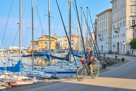 Photo for Beautiful senior woman cycling in downtown Piran in Slovenia, Europe - Royalty Free Image