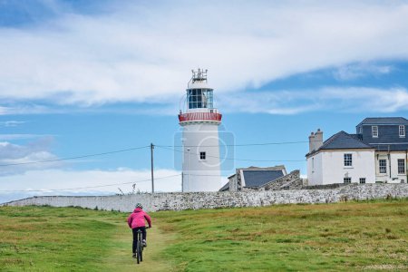 Foto de Agradable mujer mayor en bicicleta de montaña, ciclismo en Dunmore Head Lighthouse cerca de Kilballyowen, Condado de Limerick en la parte suroeste de la República de Irlanda - Imagen libre de derechos