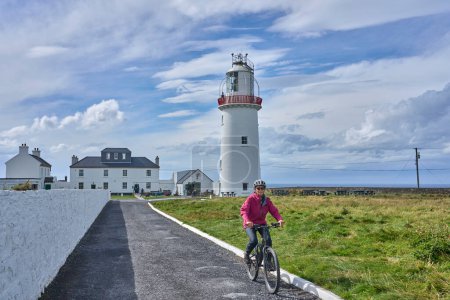 Téléchargez les photos : Belle femme âgée en VTT, faisant du vélo au phare de Dunmore Head près de Kilballyowen, comté de Limerick dans la partie sud-ouest de la Republik d'Irlande - en image libre de droit