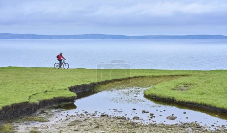 Photo for Nice senior woman on mountain bike, cycling on the cliffs of Cnoc an Daimh, Kilgalligan the northern part of thr Republic of Ireland - Royalty Free Image