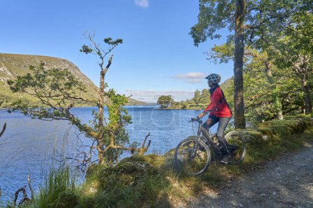 nice senior woman on mountain bike, cycling at Lough Beagh in the Glenveagh National park, near Churchill, Donegal, northern Republic of Ireland