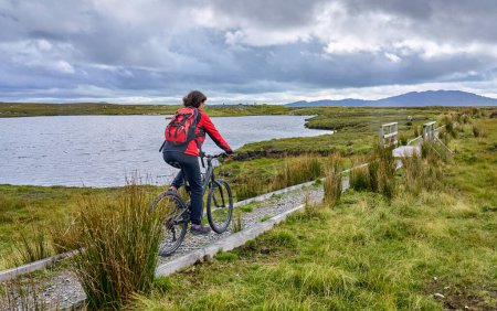 Nette Seniorin auf dem Mountainbike, Radfahren Moorgebiet in der Nähe von Derrycunlagh, County Galway, im westlichen Teil der Republik Irland