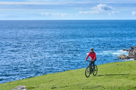 Foto de Agradable mujer mayor en bicicleta de montaña, ciclismo en los acantilados de Malin Beg Head, Donegal, norte de la República de Irlanda - Imagen libre de derechos