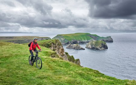 Photo for Nice senior woman on mountain bike, cycling on the cliffs of Malin Beg Head, Donegal, northern Republik of Ireland - Royalty Free Image