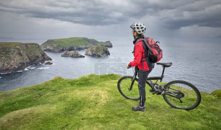 Téléchargez les photos : Belle femme âgée en VTT, vélo sur les falaises de Malin Beg Head, Donegal, nord de la Republik d'Irlande - en image libre de droit