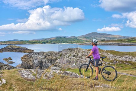 Téléchargez les photos : Belle femme âgée en VTT, vélo sur les falaises de Tooremore, comté de Cork dans le sud-ouest de l'Irlande - en image libre de droit