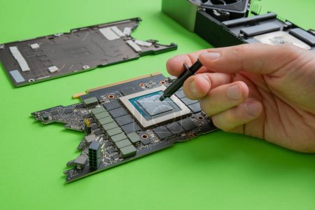 Photo for Changing the thermal paste on the graphics processor. Disassembled graphics card on the table. Old graphics card service - Royalty Free Image
