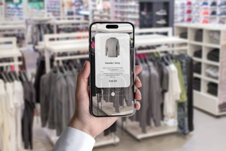 Foto de Futuro del concepto de compras en la tienda de ropa con una aplicación inteligente. Explora las características de la prenda simplemente apuntando el teléfono - Imagen libre de derechos