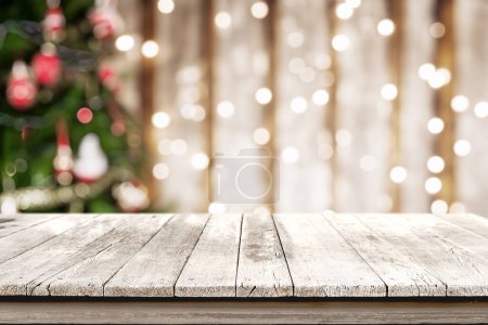 Ein sauberer weißer Holztisch für die Produktpräsentation mit einem Hintergrund aus bezaubernden Weihnachtsbaumlichtern in Bokeh. Ideales Setup für eine fesselnde und festliche Produktpräsentation