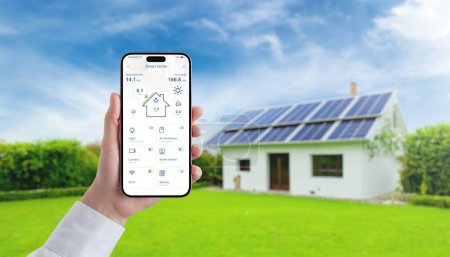 Photo for Hand holding smartphone with smart home app, monitoring solar panel energy, temperature, and home consumption, advancing the concept of efficient green living - Royalty Free Image