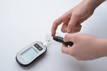 Pinchar el dedo para medir el nivel de azúcar en sangre usando dispositivos y tiras. Destacando la importancia del manejo de la diabetes, monitoreo de salud y estrategias de atención médica