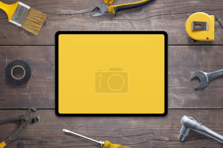Tablet mockup for app promotion, surrounded by tools on wooden table. Perfect for showcasing your app. Top view, flat lay composition. DIY concept