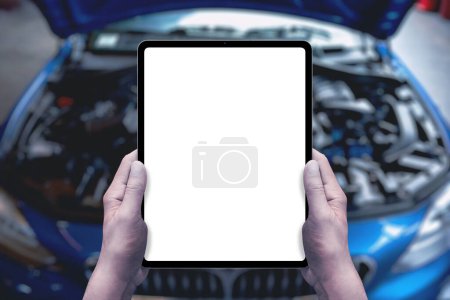 Photo for Serviceman holds a tablet in front of a car with an open engine compartment. Isolated display for service promotion, applications, parts sales - Royalty Free Image