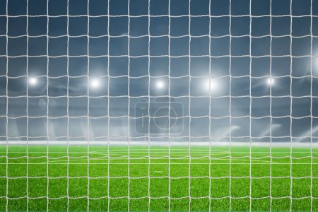 Goal net in a football stadium illuminated with lights, creating a dramatic sports scene