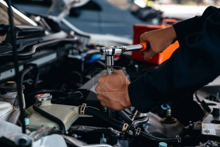 Téléchargez les photos : Mécanicien utilisant une clé lors du travail sur le moteur de voiture à l'atelier de garage. - en image libre de droit