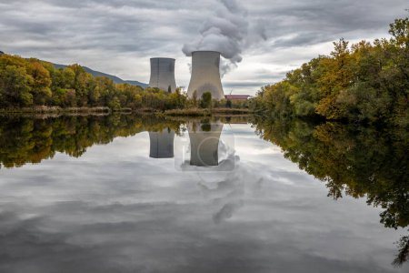 Photo for Cooling Towers of Cruas Nuclear Power Plant with Dramatic Clouds of Smoke Reflected in the Lake - Royalty Free Image