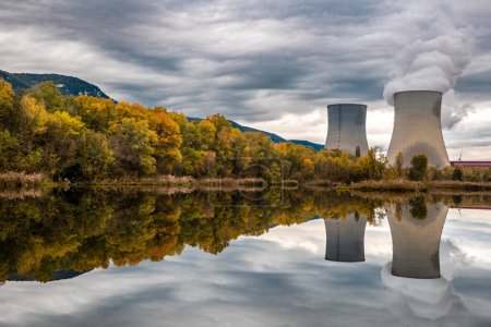 Téléchargez les photos : Tours de refroidissement de la centrale nucléaire de Cruas avec des nuages de fumée dramatiques reflétés dans le lac - en image libre de droit