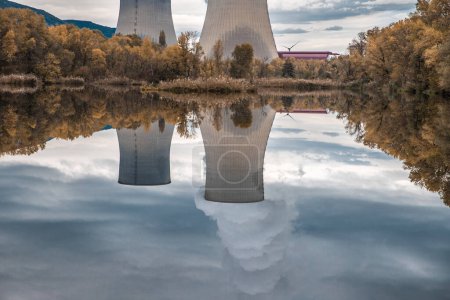 Téléchargez les photos : Tours de refroidissement de la centrale nucléaire de Cruas avec des nuages de fumée dramatiques reflétés dans le lac - en image libre de droit