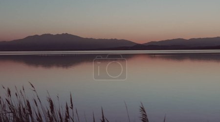 Dunstige Sonnenuntergangslandschaft der Lagune von Etan de Canet in Frankreich, Naturhintergründe Wasser und Berge 