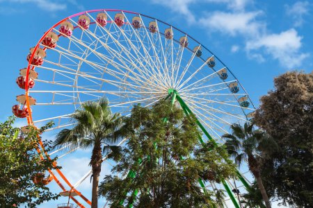 View of a Ferris wheel with colorful gondolas in Ayia Napa fun park. Cyprus, Mediterranean sea.