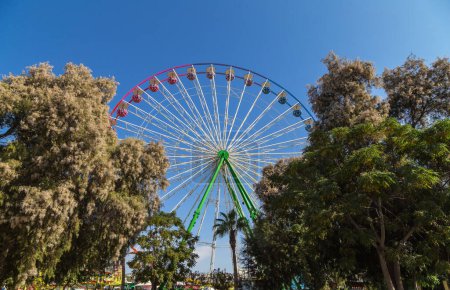 View of a Ferris wheel with colorful gondolas in Ayia Napa fun park. Cyprus, Mediterranean sea.