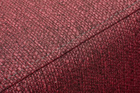Textured red furniture fabric with stitching close-up
