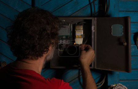 Foto de Apagado de energía, medidor eléctrico, mano en la noche tiene un partido en llamas - Imagen libre de derechos