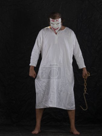 Photo for Maniac in a hockey mask in a medical gown on a black background - Royalty Free Image