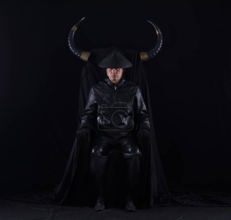 Photo for Portrait of a male devil with horns on a black throne - Royalty Free Image