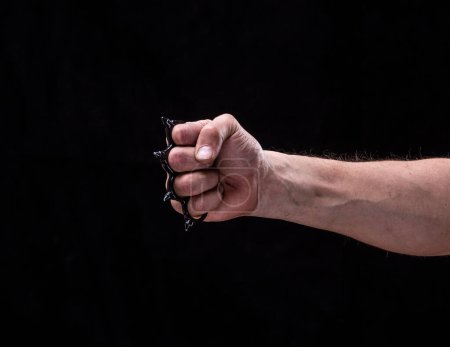 Photo for Hand with brass knuckles on a black background isolated - Royalty Free Image