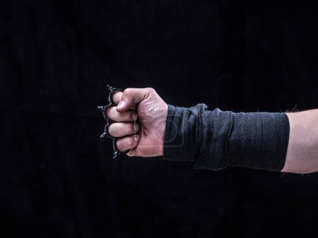 Photo for Hand with brass knuckles on a black background isolated - Royalty Free Image