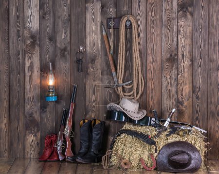 Foto de Sombrero de vaquero, botas y armas en el fondo del viejo granero. Salvaje oeste, vaquero, Vintage - Imagen libre de derechos