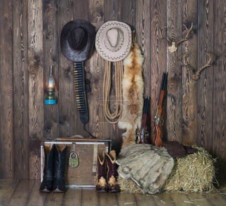 Foto de Sombrero de vaquero, botas y armas en el fondo del viejo granero. Salvaje oeste, vaquero, Vintage - Imagen libre de derechos
