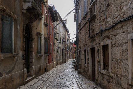 Photo for Old town alley in the Croatian town of Rovinj with old residential building fronts and freely laid power cables - Royalty Free Image