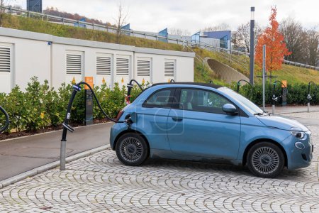 Foto de Alemania, Zusmarshausen 26.11.2022; A blue Fiat 500e convertible charges in the Sortimo charging park at the freeway - Imagen libre de derechos