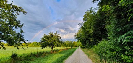 Foto de Rainbow over Thunderclouds over a field path in the morning in Siebenbrunn near Augsburg before a rain in the morning - Imagen libre de derechos