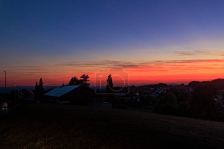 Foto de Colorful sunset in Rems-Murrkreis district in Germany with view of roof with solar panels and silhouette of tree - Imagen libre de derechos